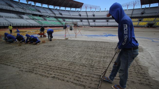 Pekerja membuat lubang untuk pemasangan bibit rumput di lapangan Stadion Gelora Bung Tomo (GBT), Surabaya, Jawa Timur, Jumat (18/9/2020).  [ANTARA FOTO/Moch Asim]
