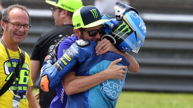 Valentino Rossi (kedua dari kanan) berpelukan dengan sang adik tiri, Luca Marini usai balapan Moto2 pada 2018 lalu. [Mohd RASFAN / AFP]