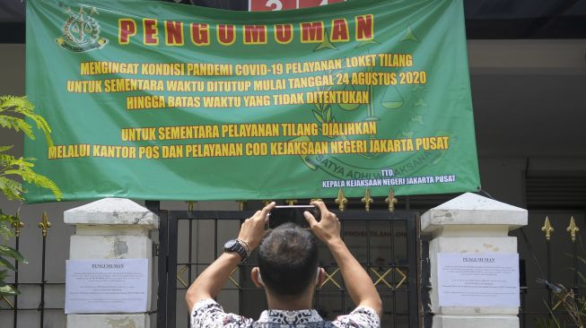 Warga memotret pengumuman pelayanan di Kantor Kejaksaan Negeri (Kejari) Jakarta Pusat yang tutup sementara di Jakarta, Jumat (18/9/2020). [ANTARA FOTO/Galih Pradipta]