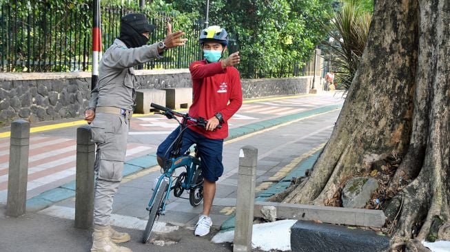 Anggota Satpol PP Kota Bogor menghentikan pengguna sepeda saat penutupan sementara pedestrian seputaran Istana dan Kebun Raya Bogor, Jawa Barat, Sabtu (19/9/2020).  [ANTARA FOTO/Arif Firmansyah]