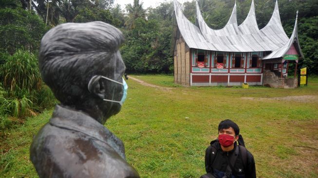 Pengunjung melihat monumen Tan Malaka yang terbuat dari perunggu dan dipasangi masker, di kawasan Museum Tan Malaka, di Nagari Pandam Gadang, Kecamatan Gunung Omeh, Kabupaten Limapuluhkota, Sumatera Barat, Sabtu (19/9/2020).  [ANTARA FOTO/Iggoy el Fitra]
