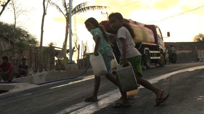 Dua orang anak menenteng jeriken berisi air bersih usai mendapatkannya pada pembagian air bersih oleh pihak kepolisian di Kecamatan Alak, Kota Kupang, NTT, Sabtu (19/9/2020). [ANTARA FOTO/Kornelis Kaha]