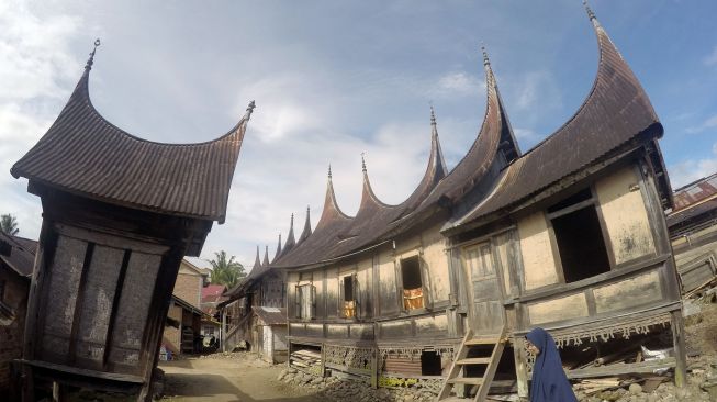 Seorang warga berjalan di depan Rumah Gadang, Kampung Adat Sarugo (Saribu Gonjong), Kabupaten Limapuluhkota, Sumatera Barat, Jumat (18/9/2020).  [ANTARA FOTO/Iggoy el Fitra]