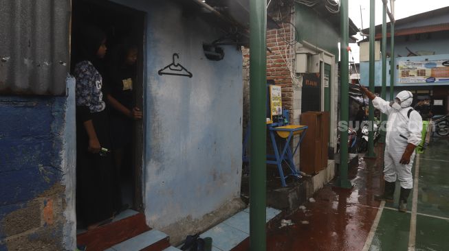 Relawan Siaga Bencana Berbasis Masyarakat (SIBAT) menyemprotkan cairan disinfektan di permukiman padat penduduk di kawasan Menteng Tenggulun, Jakarta, Minggu (20/9/2020). [Suara.com/Angga Budhiyanto]