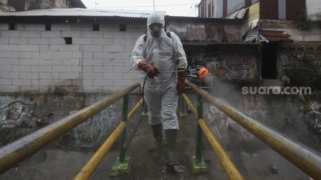 Relawan Siaga Bencana Berbasis Masyarakat (SIBAT) menyemprotkan cairan disinfektan di permukiman padat penduduk di kawasan Menteng Tenggulun, Jakarta, Minggu (20/9/2020). [Suara.com/Angga Budhiyanto]