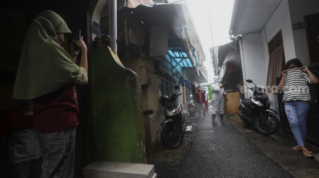 Relawan Siaga Bencana Berbasis Masyarakat (SIBAT) menyemprotkan cairan disinfektan di permukiman padat penduduk di kawasan Menteng Tenggulun, Jakarta, Minggu (20/9/2020). [Suara.com/Angga Budhiyanto]