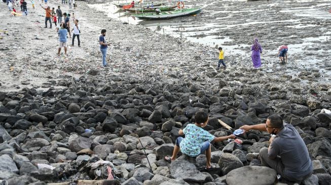 Warga bermain di pesisir pantai batu-batu Kenjeran, Surabaya, Jawa Timur, Minggu (20/9/2020). [ANTARA FOTO/M Risyal Hidayat]