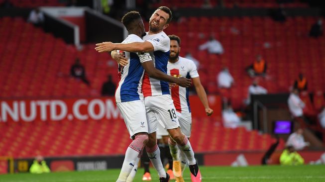 Striker Crystal Palace Wilfried Zaha (kiri) merayakan dengan gelandang Crystal Palace James McArthur (kanan) setelah mencetak gol kedua mereka selama pertandingan sepak bola Liga Premier Inggris antara Manchester United melawan Crystal Palace di Old Trafford, Manchester, Inggris, Sabtu (19/9). [Shaun Botterill / POOL / AFP]