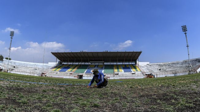 Pekerja menanam bibit rumput di lapangan Stadion Gelora 10 November di Surabaya, Jawa Timur, Senin (21/9/2020). [ANTARA FOTO/M Risyal Hidayat]