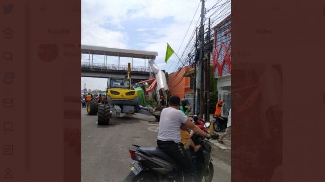 Sebuah ekskavator tersangkut di jembatan penyeberangan orang atau JPO di kawasan Kampung Melayu, Jakarta Selatan. (twitter @MrsH_125)