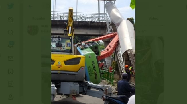 Sebuah ekskavator tersangkut di jembatan penyeberangan orang atau JPO di kawasan Kampung Melayu, Jakarta Selatan. (twitter @MrsH_125)