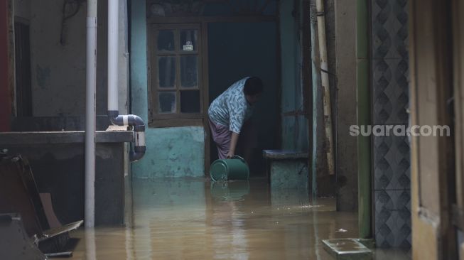 Warga membersihkan rumahnya yang terendam banjir di kawasan Kebon Pala, Kampung Melayu, Jakarta, Selasa (22/9/2020). [Suara.com/Angga Budhiyanto]