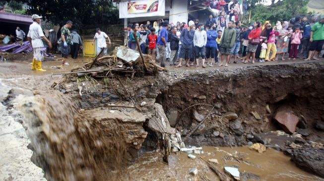 Warga melihat jalanan yang rusak pasca banjir bandang di Kampung Cibuntu, Desa Pasawahan, Kecamatan Cicurug, Sukabumi, Jawa Barat, Selasa (22/9/2020). [ANTARA FOTO/Yulius Satria Wijaya]