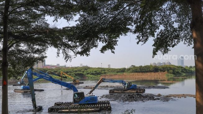 Dua alat berat sedang dioperasikan untuk  mengeruk lumpur di Waduk Ria Rio, Pulo Gadung, Jakarta Timur, Selasa (22/9). [Suara.com/Alfian Winanto]