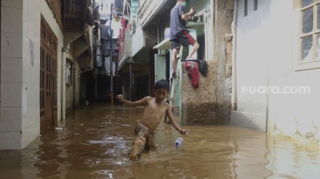 Seorang anak melintasi banjir yang merendam kawasan Kebon Pala, Kampung Melayu, Jakarta, Selasa (22/9/2020). [Suara.com/Angga Budhiyanto]