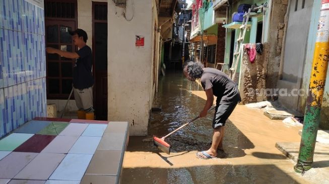 Warga di Kebon Pala, Jaktim saat membersihkan lumpur dan sisa genangan air banjir. (Suara.com/Bagaskara).