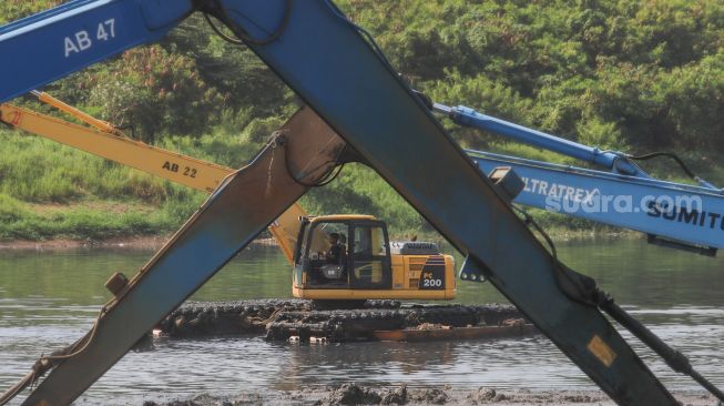 Petugas mengoperasikan alat berat untuk mengeruk lumpur di Waduk Ria Rio, Pulo Gadung, Jakarta Timur, Selasa (22/9). [Suara.com/Alfian Winanto]