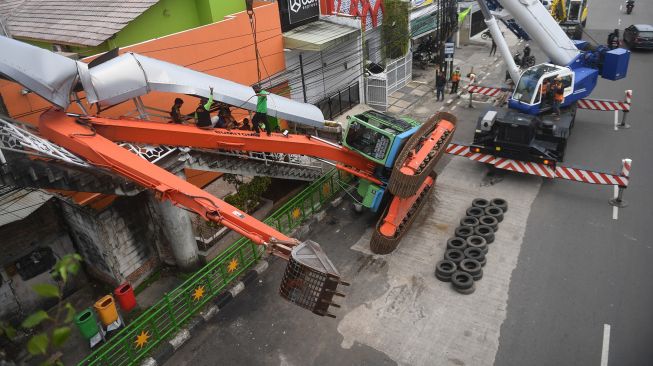 Petugas mengevakuasi ekskavator yang terguling menimpa tangga jembatan penyeberangan orang (JPO) di Kampung Melayu, Jakarta, Selasa (22/9/2020).  [ANTARA FOTO/Akbar Nugroho Gumay]
