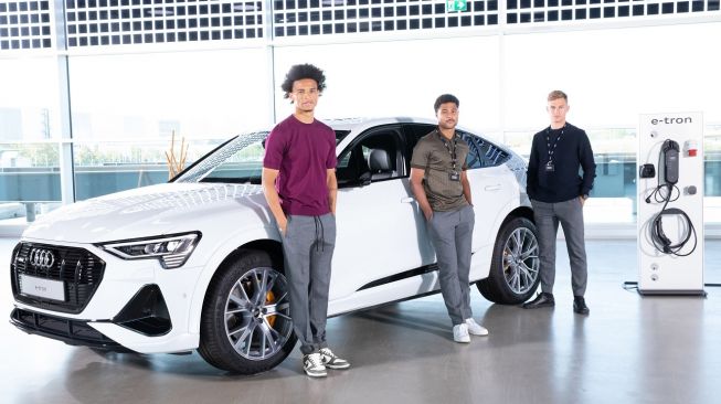 Para pemain Bayern Munich: Leroy Sane, Serge Gnabry, dan Joshua Kimmich berfoto di depan sebuah mobil listrik Audi E-Tron. [Dok Audi]