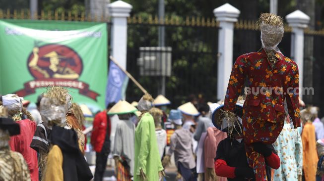 Seorang massa yang tergabung dalam Komite Nasional Pembaruan Agraria (KNPA) membawa boneka jerami atau orang-orangan sawah saat menggelar aksi Hari Tani Nasional  di depan gedung DPR RI, Jakarta, Kamis (24/9/2020). [Suara.com/Angga Budhiyanto]