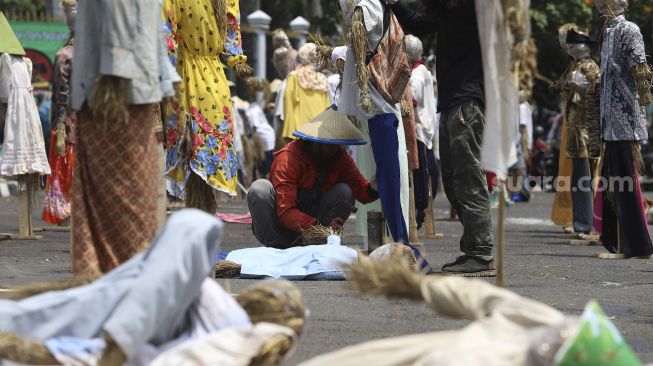 Massa yang tergabung dalam Komite Nasional Pembaruan Agraria (KNPA) memasang boneka jerami atau orang-orangan sawah saat menggelar aksi Hari Tani Nasional  di depan gedung DPR RI, Jakarta, Kamis (24/9/2020). [Suara.com/Angga Budhiyanto]