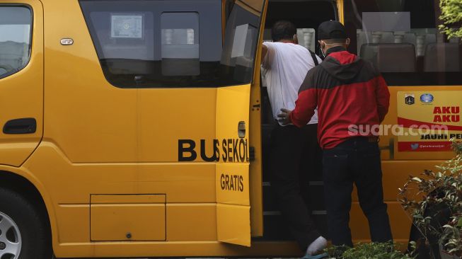 Pasien tanpa gejala COVID-19 memasuki bus sekolah yang dioperasikan Dinas Perhubungan DKI Jakarta yang mengantar dari Puskesmas Kecamatan Makassar, Jakarta, Kamis (24/9/2020). [Suara.com/Angga Budhiyanto]