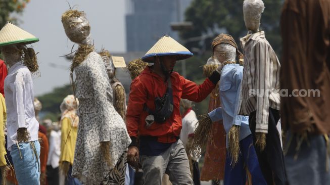 Massa yang tergabung dalam Komite Nasional Pembaruan Agraria (KNPA) memasang boneka jerami atau orang-orangan sawah saat menggelar aksi Hari Tani Nasional  di depan gedung DPR RI, Jakarta, Kamis (24/9/2020). [Suara.com/Angga Budhiyanto]