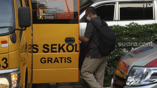 Keluarga pasien tanpa gejala COVID-19 membantu menaikkan barang bawaan pasien ke dalam bus sekolah di Puskesmas Kecamatan Makassar, Jakarta, Kamis (24/9/2020). [Suara.com/Angga Budhiyanto]