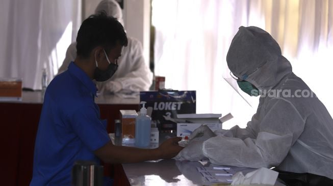 Petugas medis melakukan rapid test massal kepada pengemudi dan kernet bus di Pool Bus Doa Ibu, Ciracas, Jakarta, Jumat (25/9/2020). [Suara.com/Angga Budhiyanto]