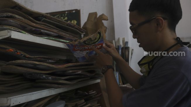 Reynanto Akhmad Aditya (35) memilah papan skateboard yang akan dibuat kacamata kayu di workshopnya di kawasan Kramat Jati, Jakarta, Jumat (25/9/2020). [Suara.com/Angga Budhiyanto]