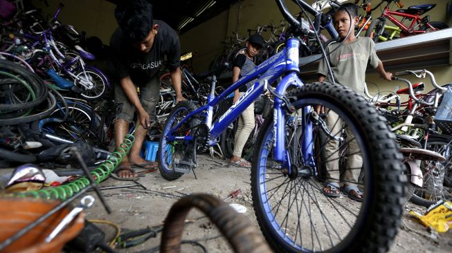 Pedagang memperbaiki sepeda bekas untuk dijual kembali di tokonya di Jalan Banda Aceh-Medan, Desa Pagar Air, Aceh Besar, Aceh, Sabtu (26/9/2020).  [ANTARA FOTO/Irwansyah Putra]
