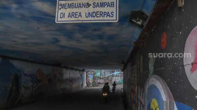 Warga melintasi Terowongan Dipo KRL yang gelap dengan kendaraannya di Pancoran Mas, Depok, Jawa Barat, Sabtu (26/9). [Suara.com/Alfian Winanto]