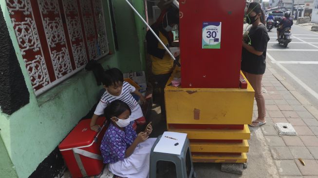 Siswi kelas 2 SDN 01 Pagi Bukit Duri Keysha Nayara Effeni (8) belajar secara online ditemani ibunya Okta (31) di gerai makanan tempat Ibunya berjualan di kawasan Bukit Duri, Jakarta, Kamis (30/7/2020). [Suara.com/Angga Budhiyanto]