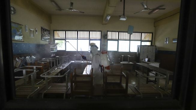 Petugas Palang Merah Indonesia (PMI) Jakarta Pusat menyemprotkan cairan disinfektan di lingkungan Sekolah Dasar Negeri (SDN) Bendungan Hilir 09 Jakarta Pusat, Senin (22/6/2020). [Suara.com/Angga Budhiyanto]