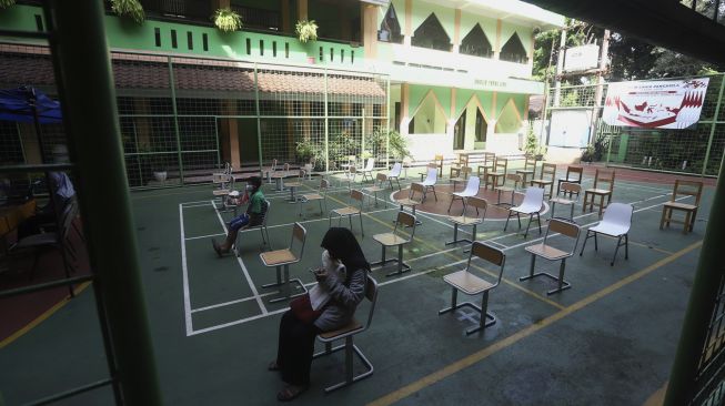 Sejumlah calon siswa menunggu dengan menjaga jark fisik di posko Penerimaan Peserta Didik Baru (PPDB) di SMK Negeri 15, Jakarta, Kamis (25/6/2020). [Suara.com/Angga Budhiyanto]