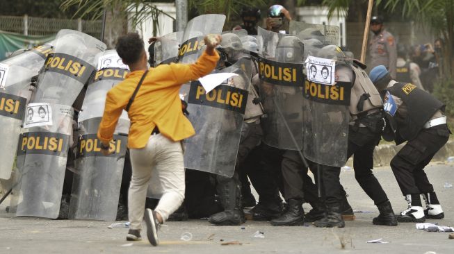 Seorang mahasiswa Universitas Haluoleo Kendari melempar batu ke aparat kepolisian saat unjuk rasa menuntut penuntasan kasus kematian dua rekannya di depan Polda Sulawesi Tenggara, Kendari, Sulawesi Tenggara, Sabtu (26/9/2020). [ANTARA FOTO/Jojon]