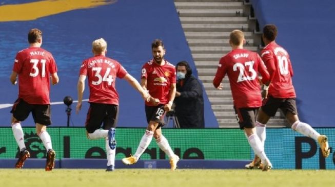 Para pemain Manchester United merayakan gol Bruno Fernandes (tengah) ke gawang Brighton and Hove Albion dari titik penalti saat laga Liga Inggris di American Express Community Stadium. JOHN SIBLEY / POOL / AFP