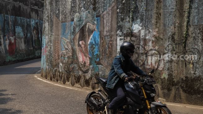 Mural dan dinding jalan yang kotor menghiasi jalan Terowongan Dipo KRL di Pancoran Mas, Depok, Jawa Barat, Sabtu (26/9). [Suara.com/Alfian Winanto]