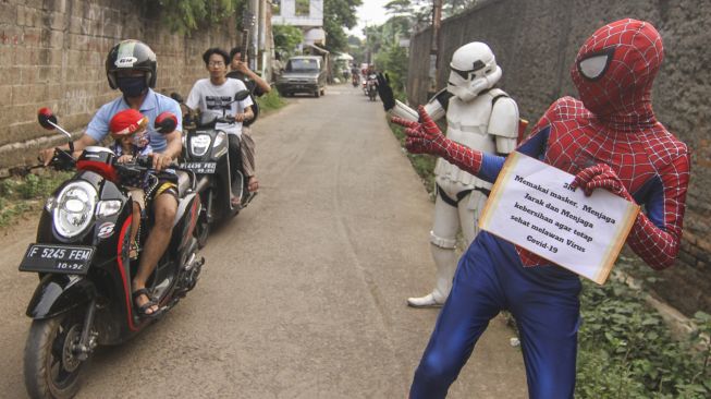 Super hero ngamen keliling kampung sambil sosialisasi protokol kesehatan di Kawasan Tapos, Depok, Jawa Barat, Minggu (27/9/2020). [ANTARA FOTO/Asprilla Dwi Adha]