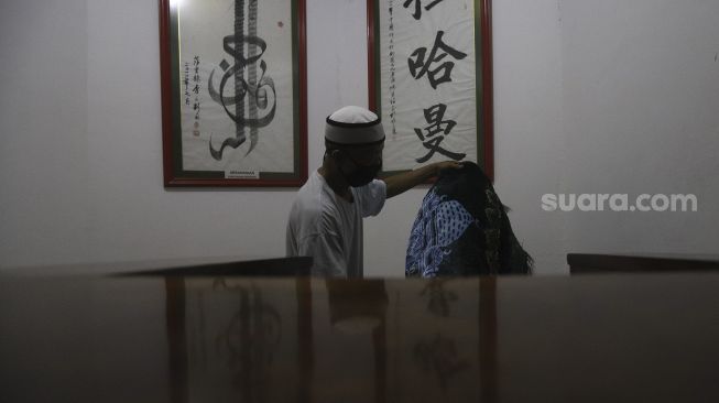 Pengurus masjid merapikan sajadah di Masjid Lautze, Sawah Besar, Jakarta, Senin (28/9/2020). [Suara.com/Angga Budhiyanto]