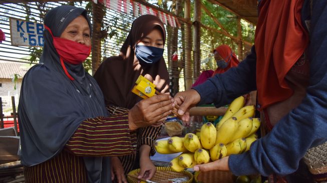 Penjual melayani pembeli di Pasar Pundensari di Desa Gunungsari Kabupaten Madiun, Jawa Timur, Minggu (27/9/2020).   [ANTARA FOTO/Siswowidodo]