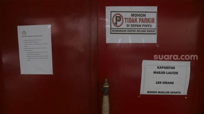 Kertas pengumuman pembatasan kapasitas terpasang di pintu masuk Masjid Lautze, Sawah Besar, Jakarta, Senin (28/9/2020). [Suara.com/Angga Budhiyanto]