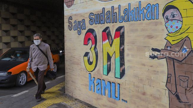 Warga melintas didepan mural Covid-19 di Terowongan Stasiun Cawang, Tebet, Jakarta Selatan, Senin (28/9). [Suara.com/Alfian Winanto]