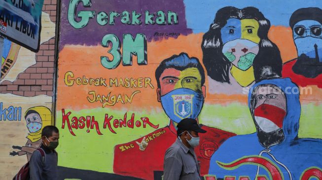 Warga melintas didepan mural Covid-19 yang berisi himbauan memakai masker di Terowongan Stasiun Cawang, Tebet, Jakarta Selatan, Senin (28/9). [Suara.com/Alfian Winanto]