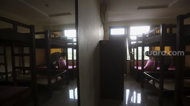 Petugas merapikan kamar yang dipersiapkan untuk tempat isolasi pasien tanpa gejala COVID-19 di Graha Wisata Ragunan, Jakarta, Rabu (30/9/2020). [Suara.com/Angga Budhiyanto]