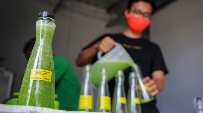 Seorang pengusaha travel menuangkang jus pakcoy ke dalam botol di kediamannya di Permata Permai, Cisaranten Kulon, Bandung, Jawa Barat, Kamis (1/10/2020).  [ANTARA FOTO/Raisan Al Farisi]