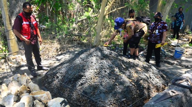 Kepala Seksi Energi Dinas ESDM wilayah Kendeng Selatan Sinung Sugeng Arianto (tengah) mengecek kadar gas di lokasi semburan air dan gas di Desa Manggarmas, Godong, Grobogan, Jawa Tengah, Jumat (2/10/2020). [ANTARA FOTO/Yusuf Nugroho]
