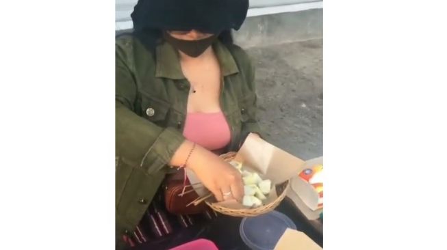 Perempuan semok mengenakan baju pink jual sate babi di pinggir jalan di Bali. (@denpasarnow)