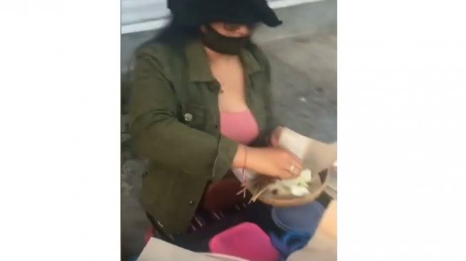 Perempuan semok mengenakan baju pink jual sate babi di pinggir jalan di Bali. (@denpasarnow)