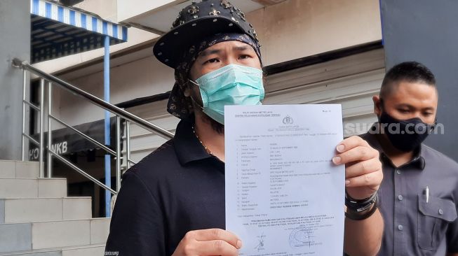 Youtuber dan Tatoo Artist Hendric Shinigami memperlihatkan surat laporan kepolisian terkait pencemaran nama baik di Polda Metro Jaya, Jakarta Selatan, Sabtu (3/10). [Suara.com/Alfian Winanto]